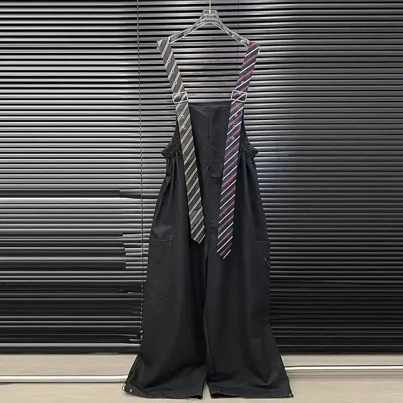 Alt Tag: Executive Street Suspender Jumpsuit black wide-leg high-waist jumpsuit with detachable tie-style suspenders hanging on hanger