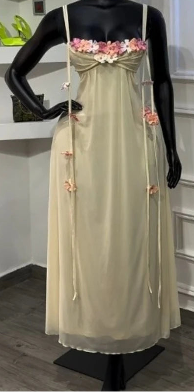 Mannequin wearing a beige dress with floral details in a room setting.