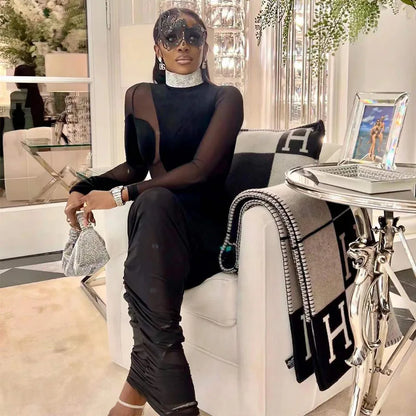 Model wearing a black velvet illusion maxi dress set and accessorized with stylish sunglasses and a chic handbag.