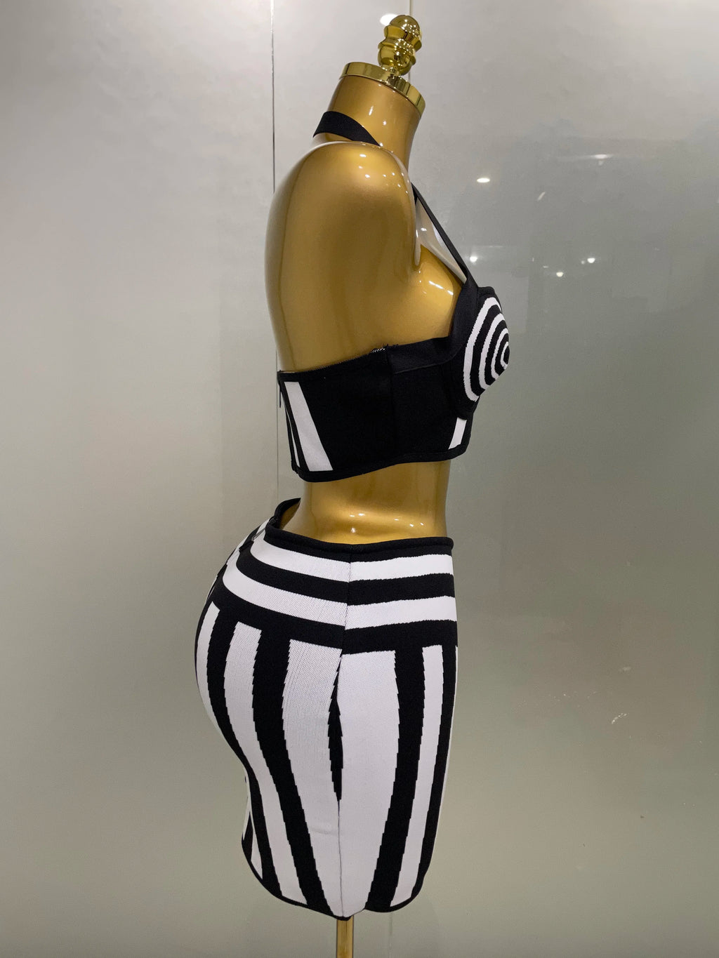 Optical Illusion Halter Bandage 2-Piece Set side view on mannequin, black-and-white halter top with spiral cups and striped skirt
