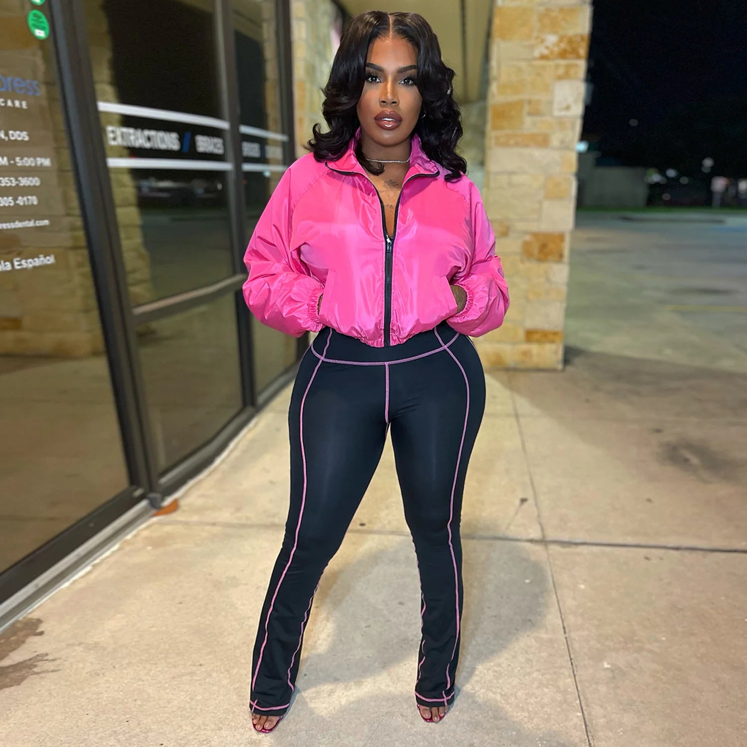 Model wearing a Velocity Luxe Zip-Front Active Set featuring a glossy cropped jacket and contrast stitch leggings.