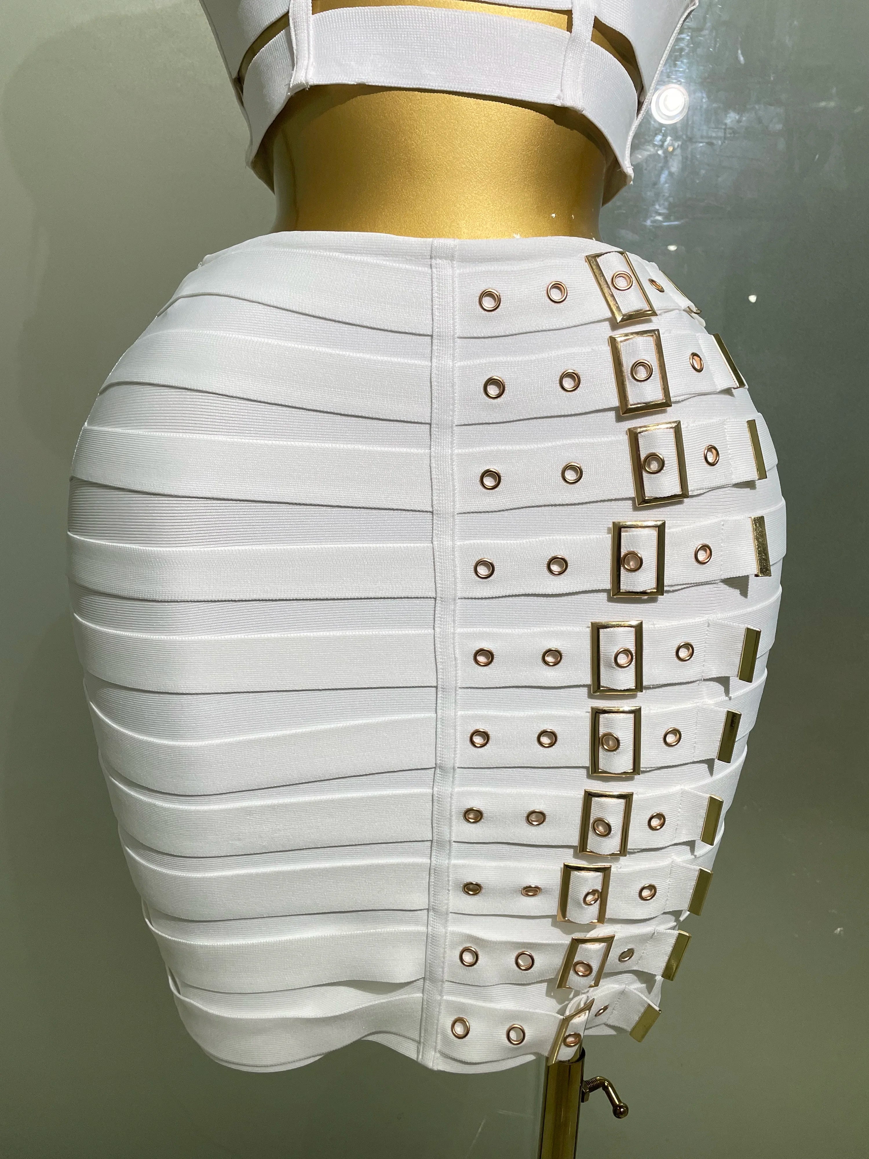 Alt Tag: Sculpted Buckle Bandage 2-Piece Set white bandage skirt with sculpted buckle straps and grommet detailing, body-hugging fit