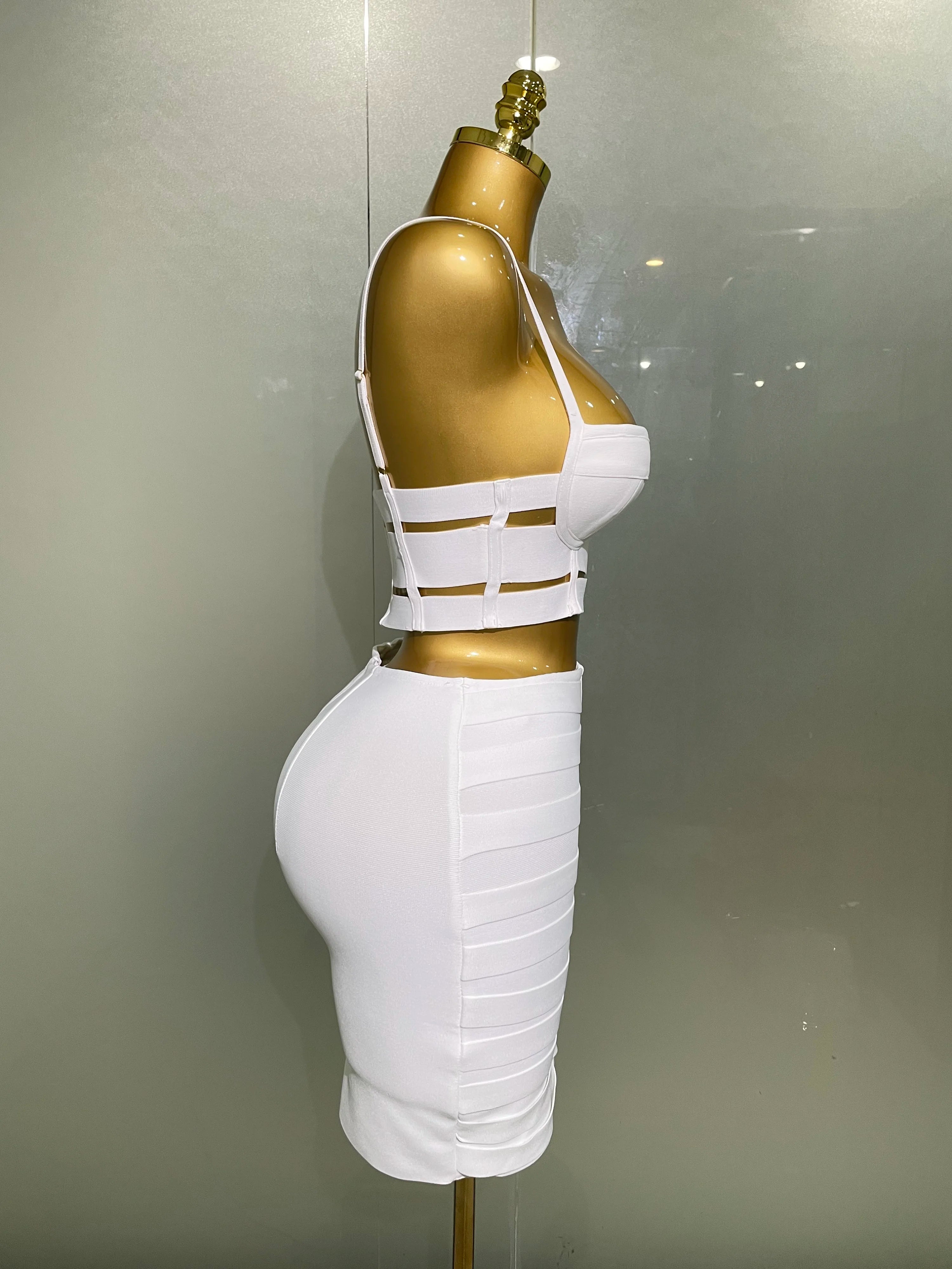 Alt Tag: Sculpted Buckle Bandage 2-Piece Set white bandage bustier crop top and skirt with cut-out waist straps on mannequin, side view