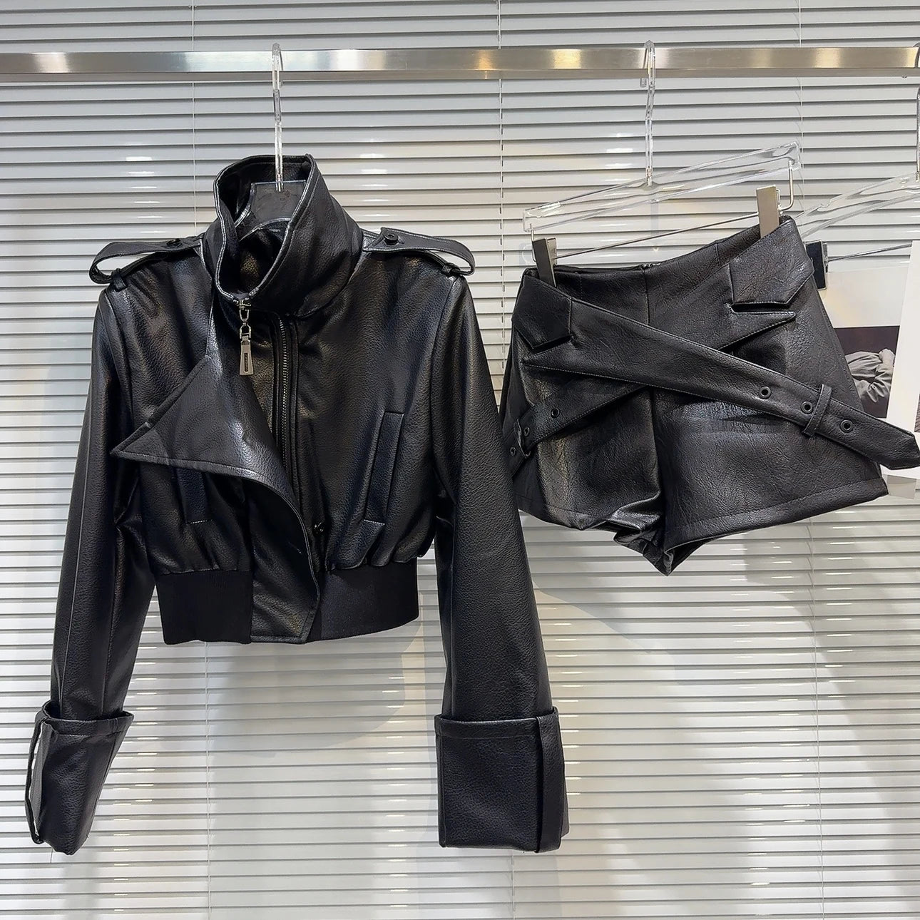 faux leather mini set with jacket and shorts displayed on hangers in a stylish boutique setting.