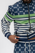 Model wearing a chain link track suit featuring a long sleeve zip jacket and matching jogger pants.