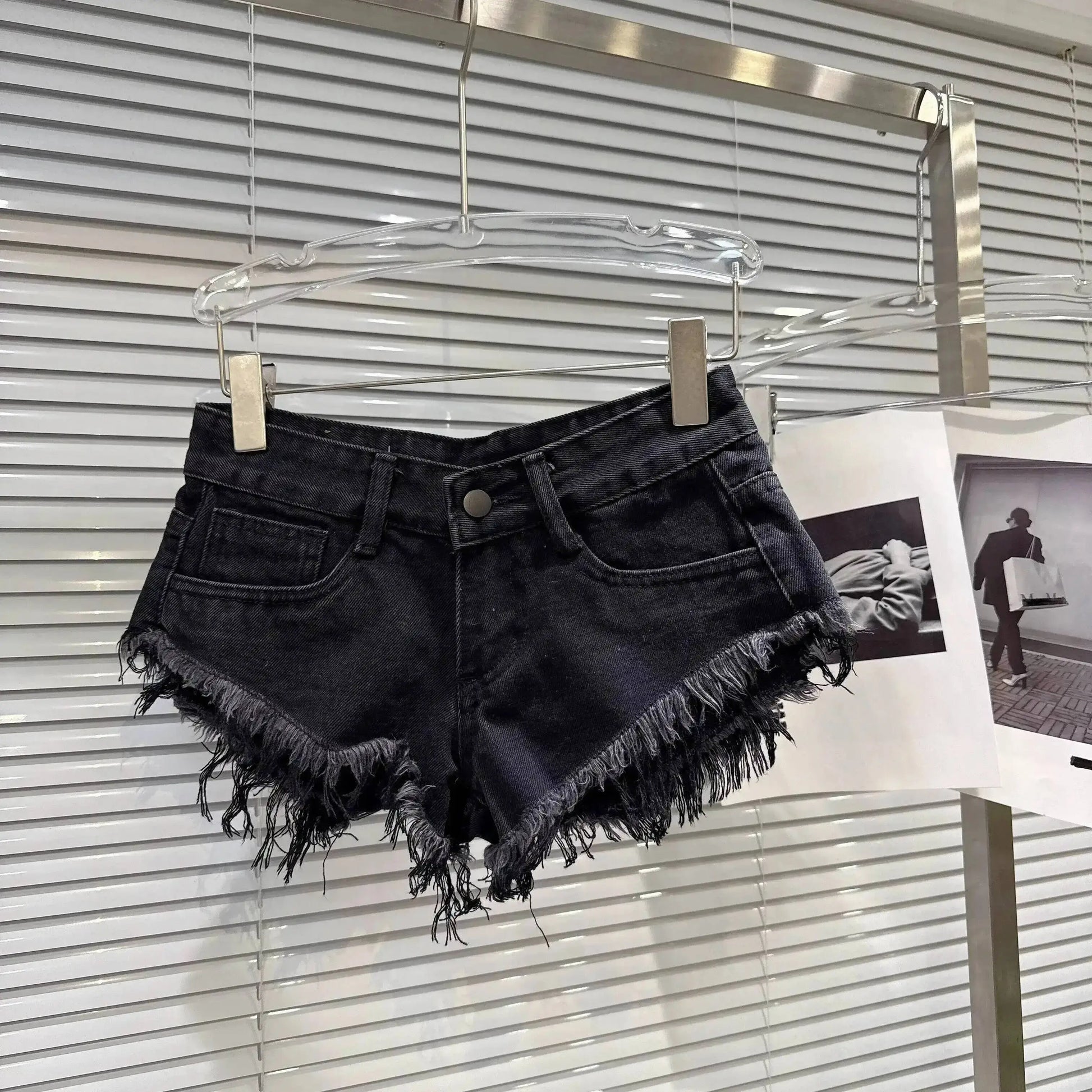 Distressed Raw-Hem Low-Rise Denim Shorts hanging on display with frayed hem and fitted low-rise waist.