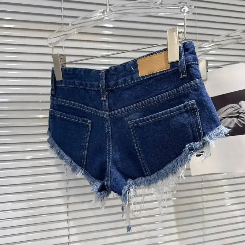 Distressed Raw-Hem Low-Rise Denim Shorts hanging on a rack showcasing the frayed hem and back pockets.