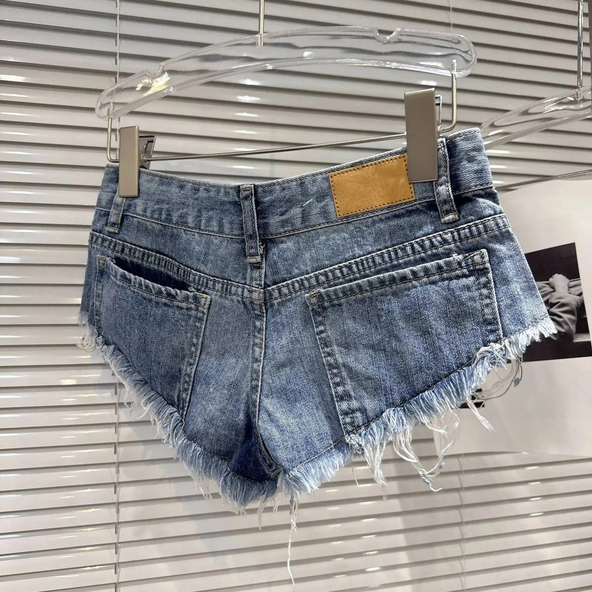 Distressed Raw-Hem Low-Rise Denim Shorts showcasing the frayed hem and fitted low-rise design from the back.