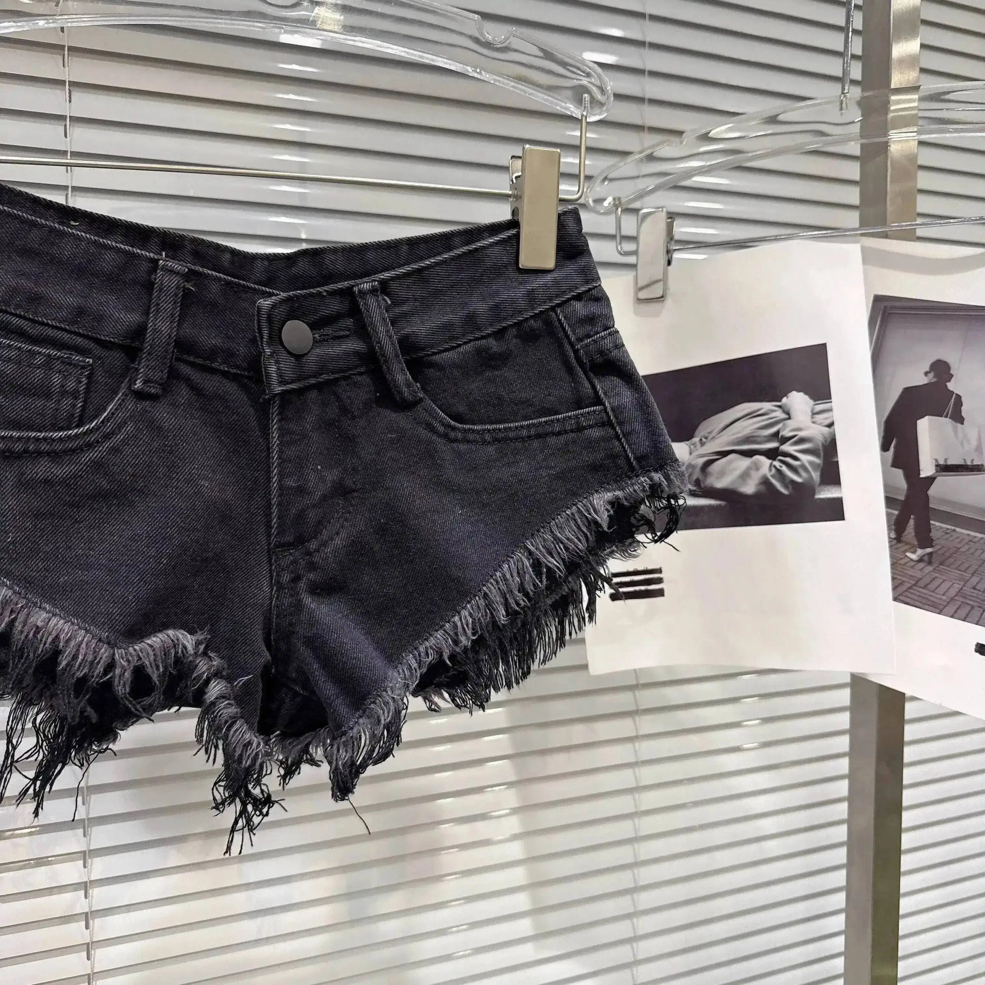 Distressed Raw-Hem Low-Rise Denim Shorts displayed on a hanger, showcasing frayed hem and low-rise fit.