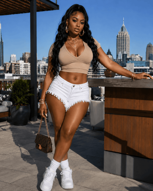 Model in Distressed Raw-Hem Low-Rise Denim Shorts with cropped top, posing outdoors against a city skyline.