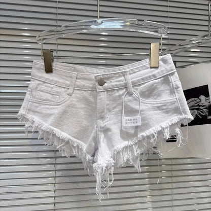 Distressed Raw-Hem Low-Rise Denim Shorts in white with frayed hem and low-rise waist hanging on display.