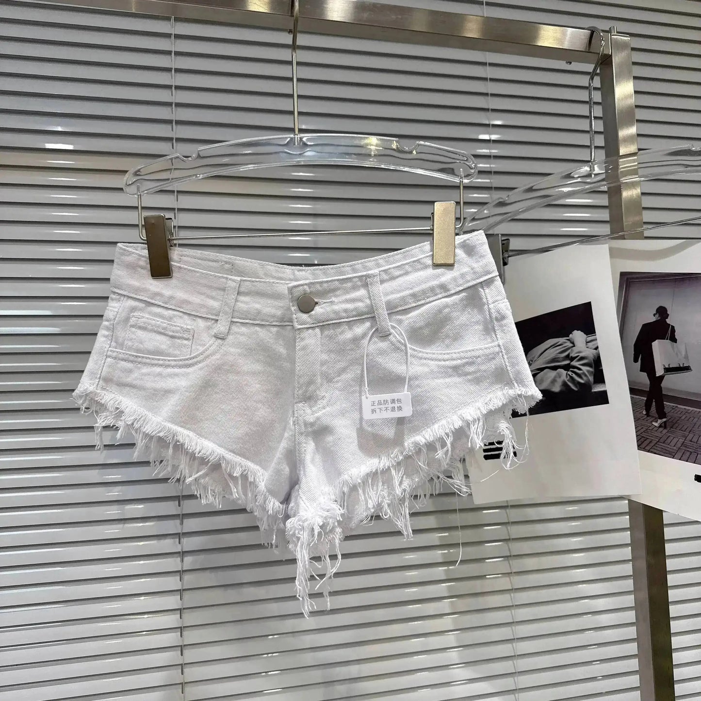 Distressed Raw-Hem Low-Rise Denim Shorts displayed on a hanger with frayed edges and a low-rise waist.