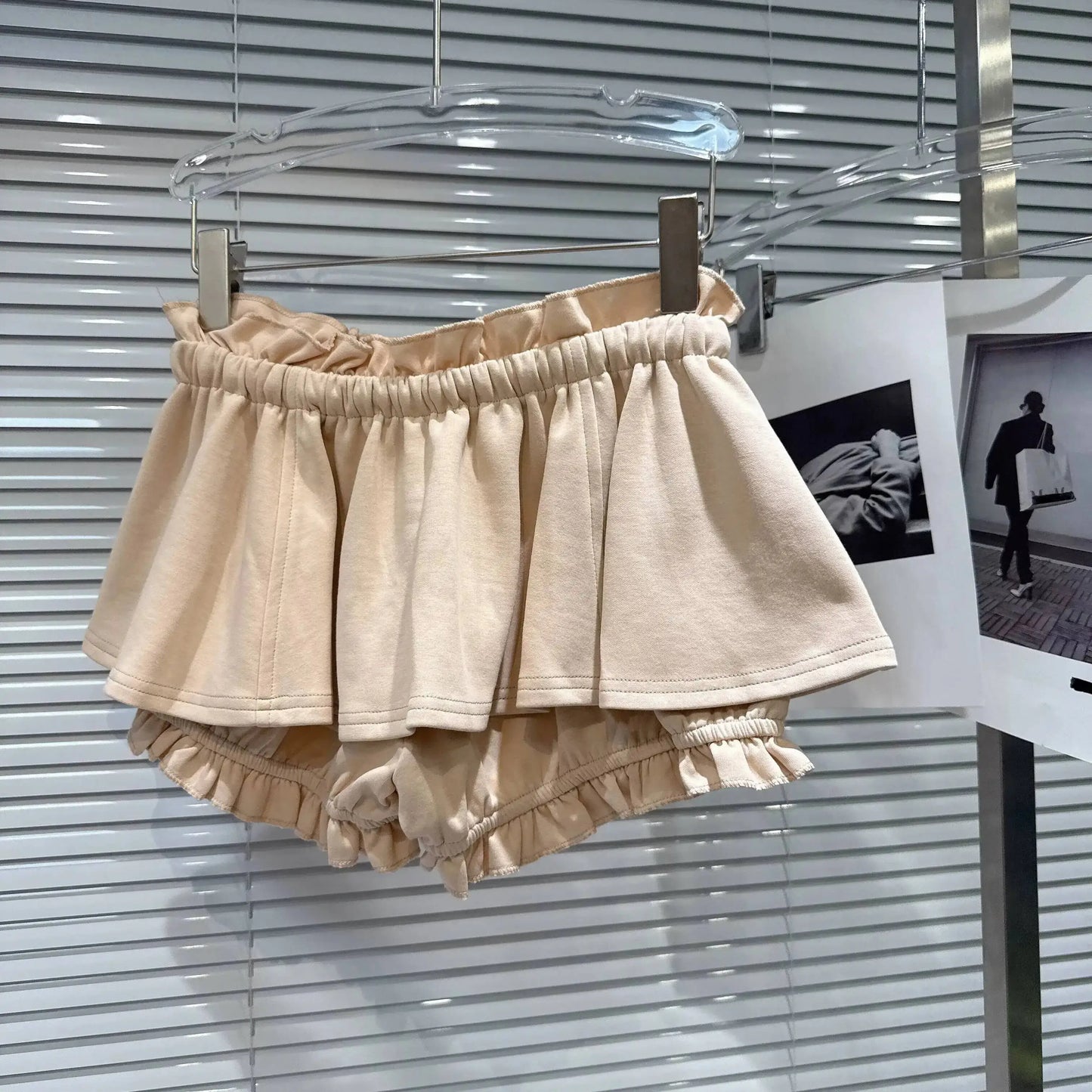 Layered Ruffle Drawstring Mini Skort in beige hanging on display with ruffled hem and elastic waistband.