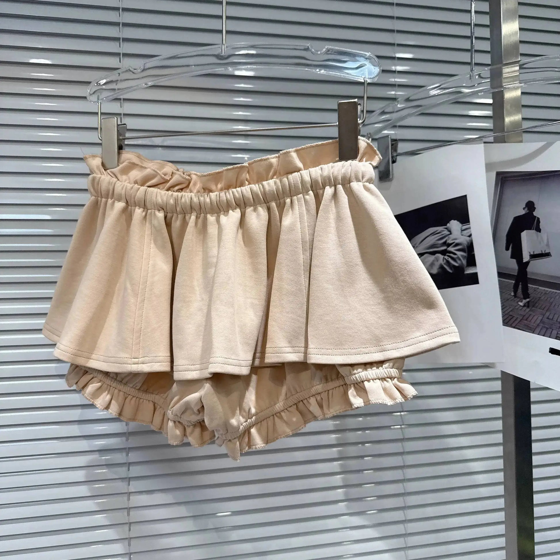 Layered Ruffle Drawstring Mini Skort in beige hanging on display with ruffled hem and elastic waistband.