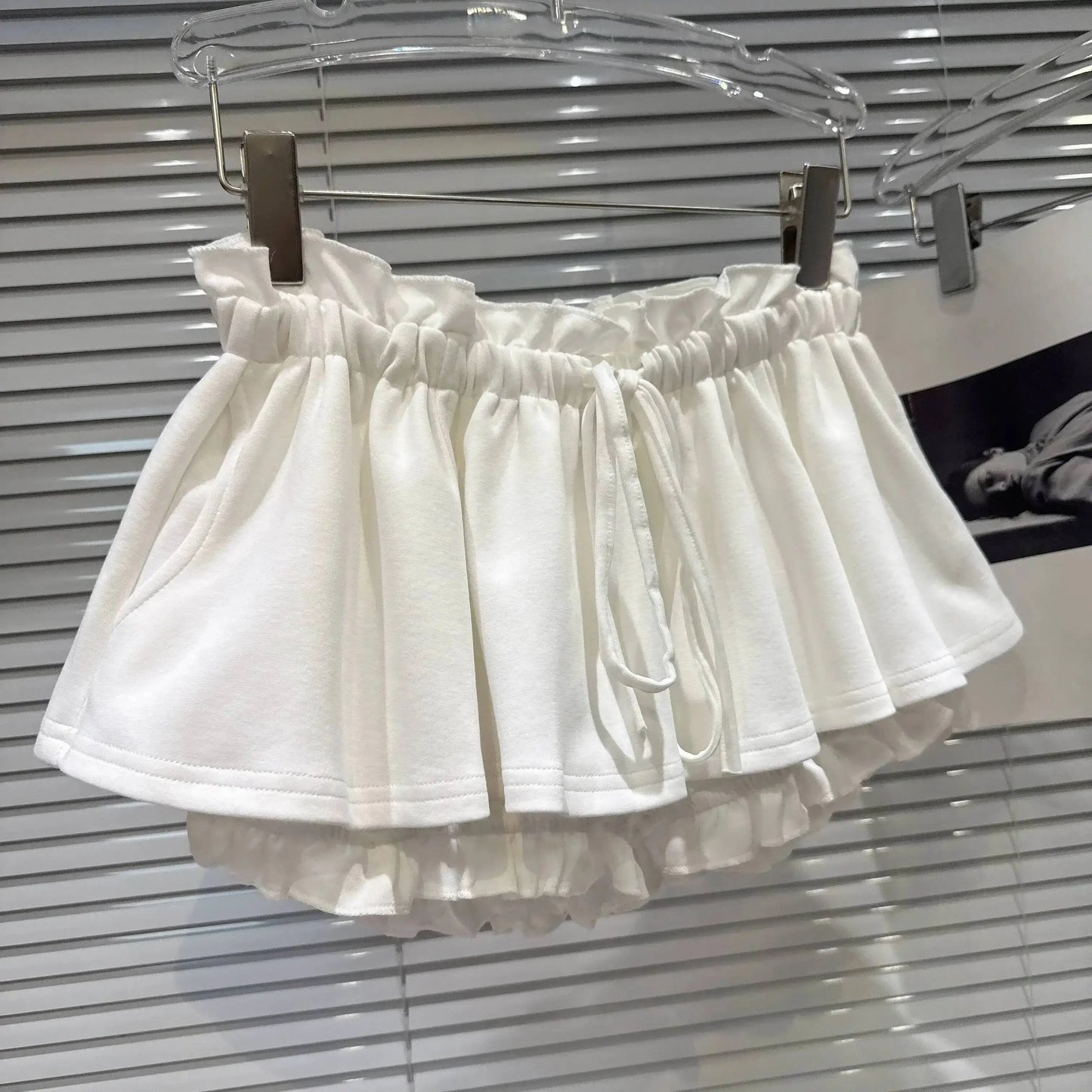 Layered Ruffle Drawstring Mini Skort displayed on hanger in white with ruffled layers and adjustable drawstring waistband.