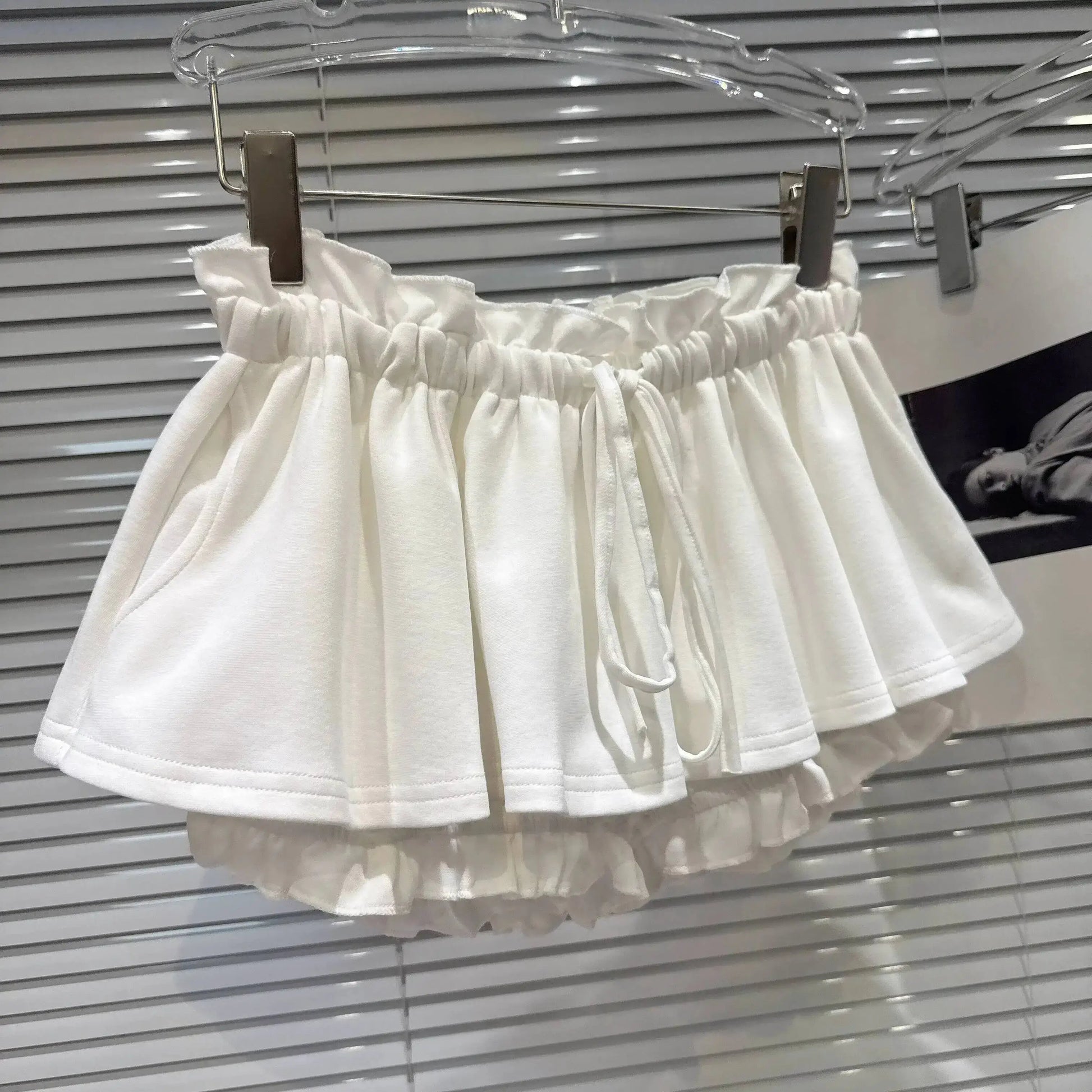 Layered Ruffle Drawstring Mini Skort displayed on hanger in white with ruffled layers and adjustable drawstring waistband.