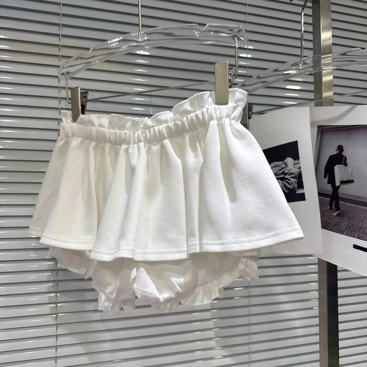 Layered Ruffle Drawstring Mini Skort displayed on a hanger showing white layered ruffles and shorts underneath.