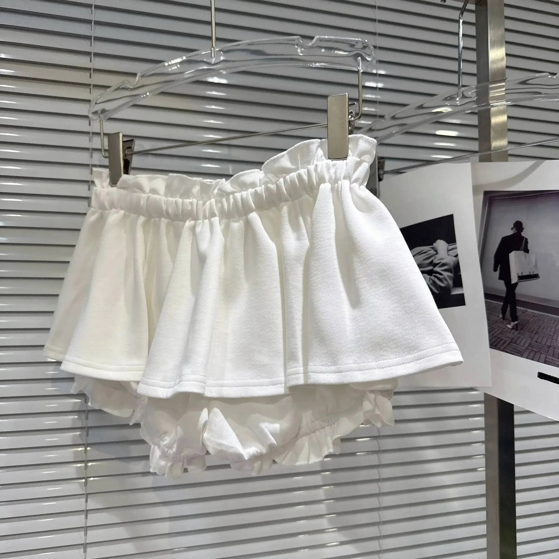 Layered Ruffle Drawstring Mini Skort displayed on a hanger showing white layered ruffles and shorts underneath.
