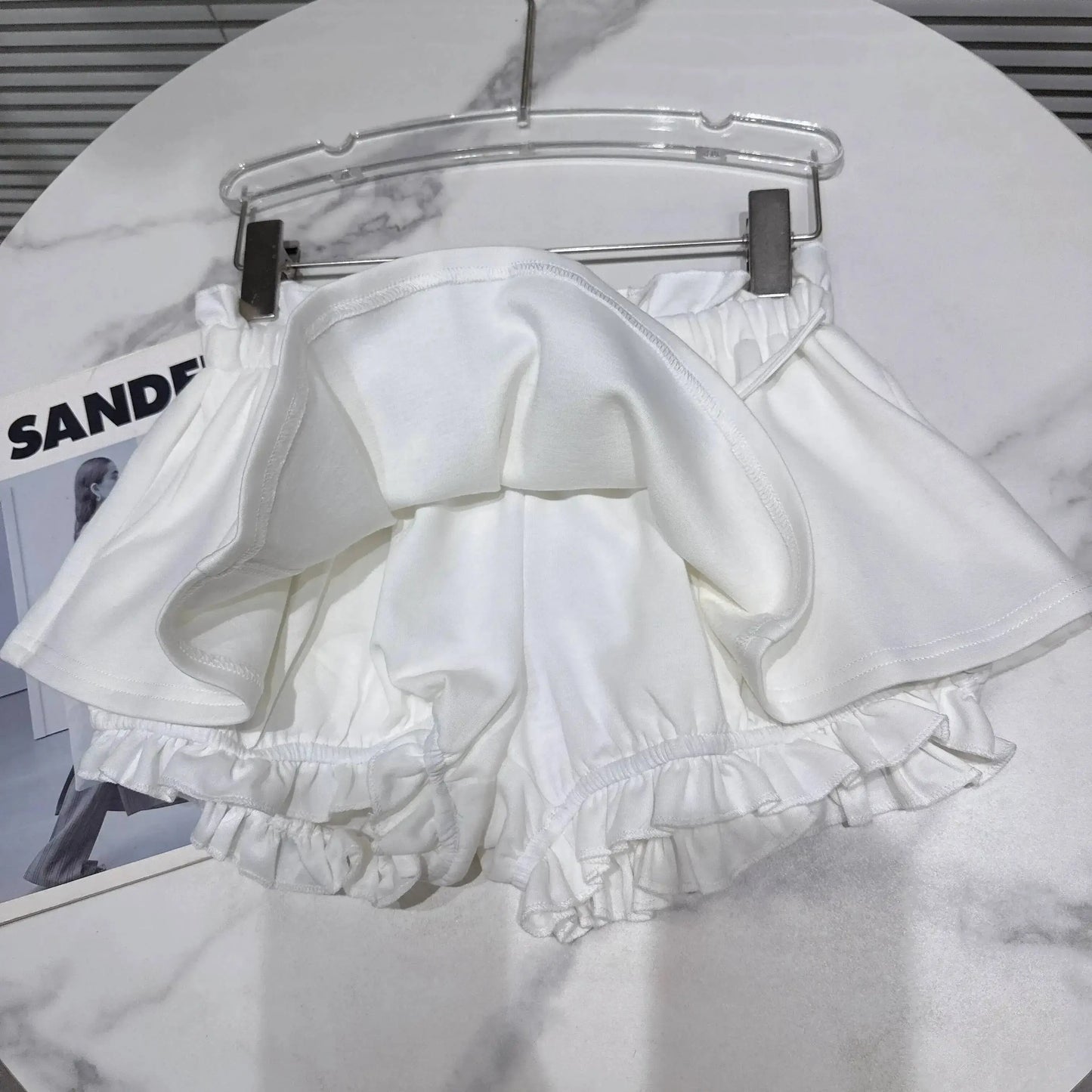 Layered Ruffle Drawstring Mini Skort displayed on a hanger, showcasing the ruffled design and shorts underlayer.