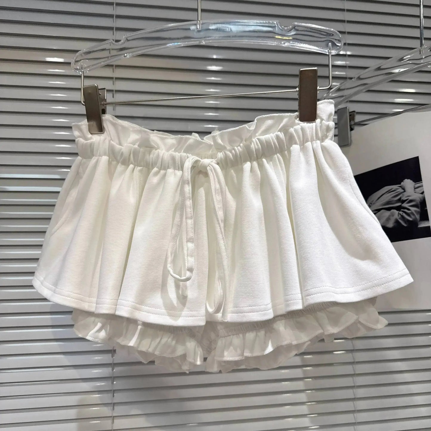 Layered Ruffle Drawstring Mini Skort hanging display in white, showcasing layered ruffles and drawstring detail.