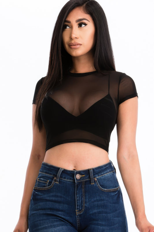 Model wearing a sheer mesh crop top paired with high-waisted jeans, showcasing a stylish look.