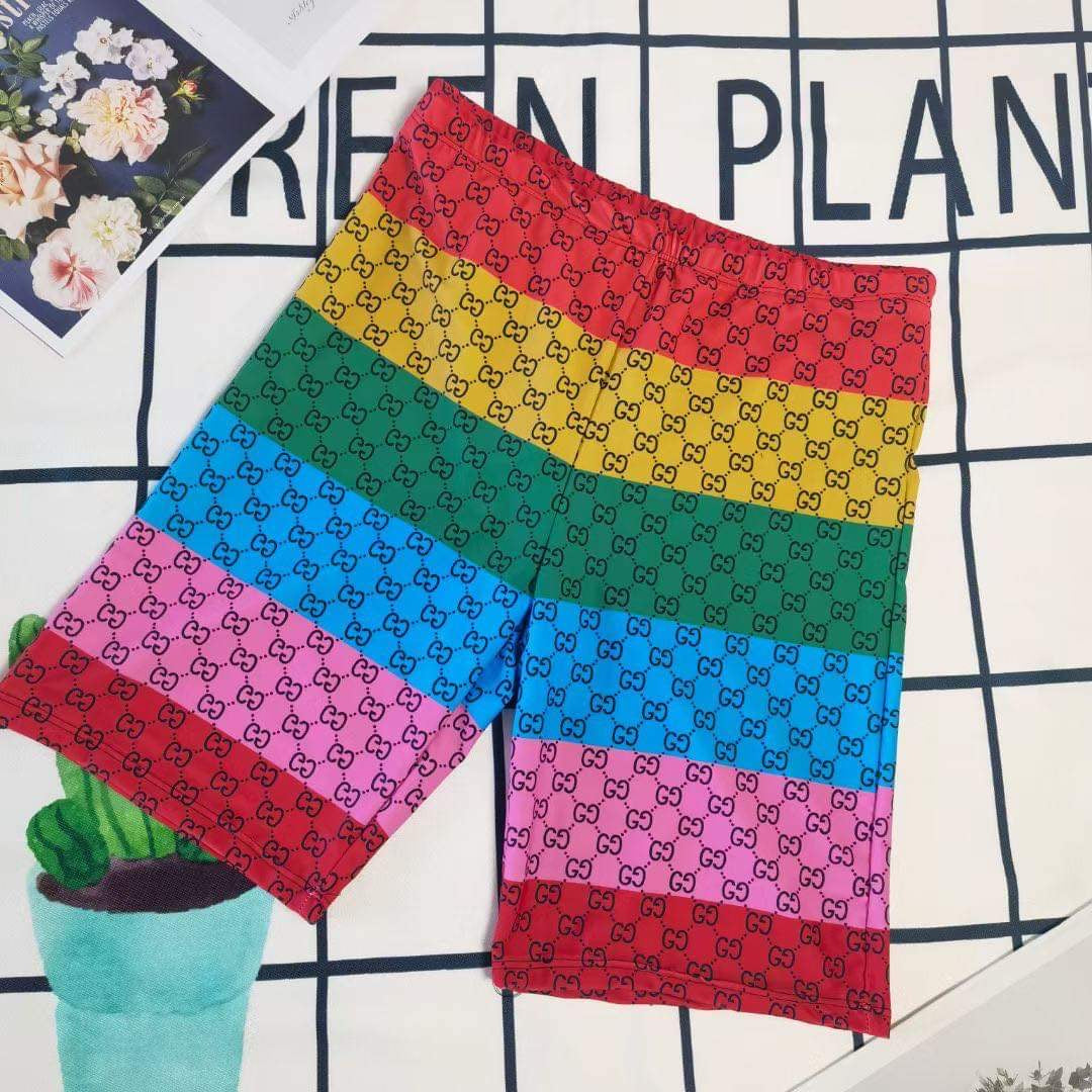 His and Her Matching Monogram Swimwear featuring bold multicolor prints on swim shorts.