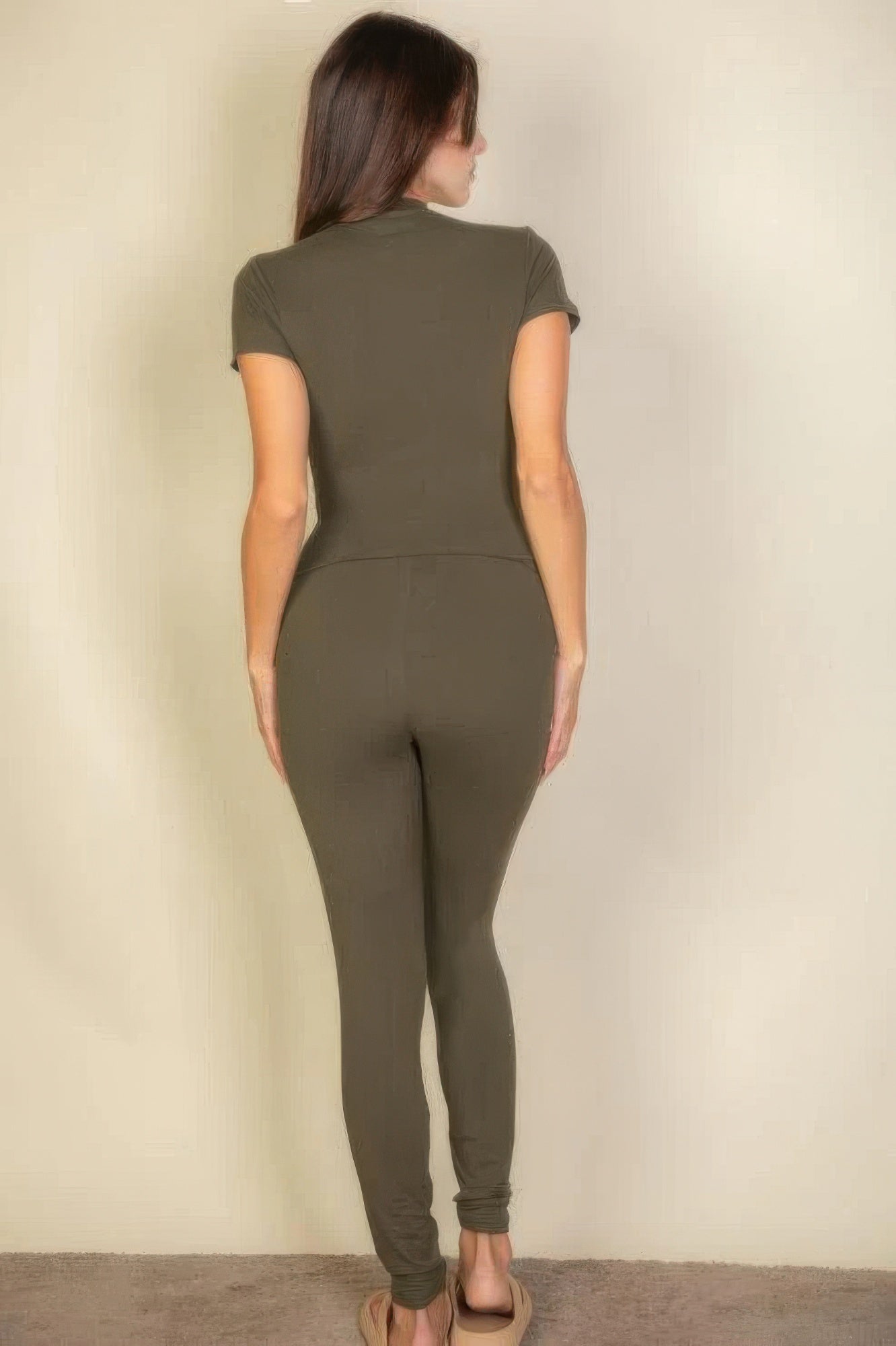 Back view of a woman wearing an olive green short sleeve two-piece legging set, showcasing a fitted design.