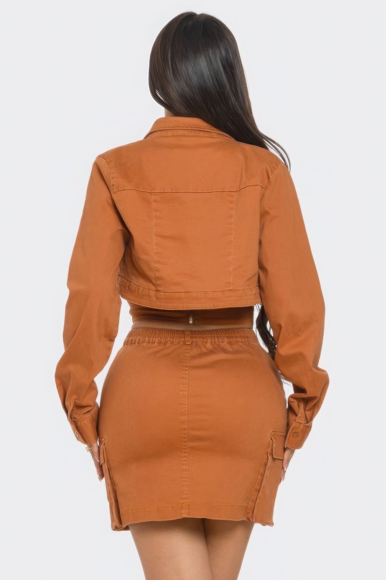 Stylish three piece skirt set featuring a fitted skirt, chic top, and matching crop jacket in a warm orange color.
