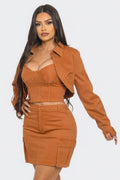 Model showcasing a stylish three piece skirt set with crop jacket in a warm orange hue.