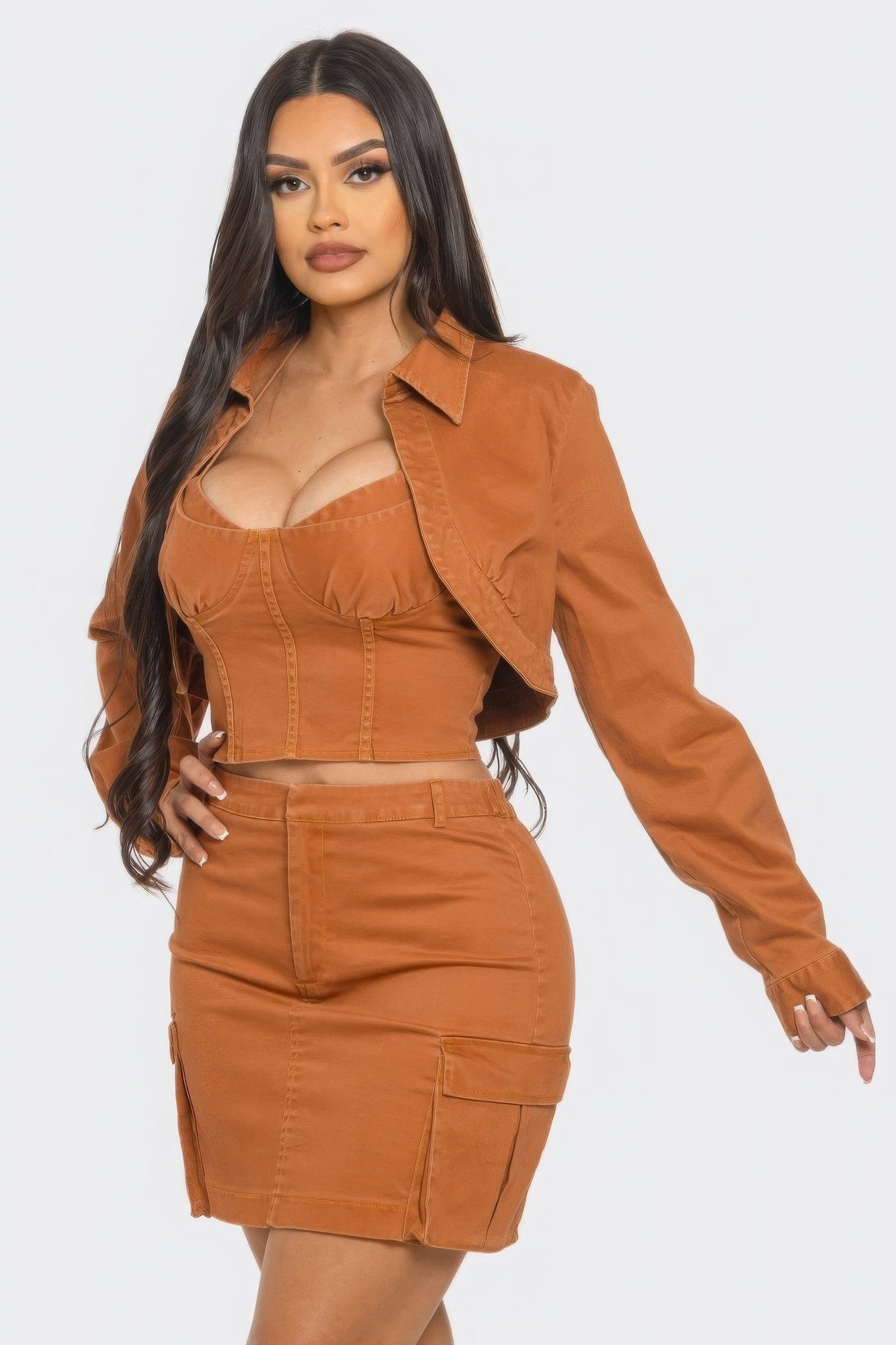 Model showcasing a stylish three piece skirt set with crop jacket in a warm orange hue.