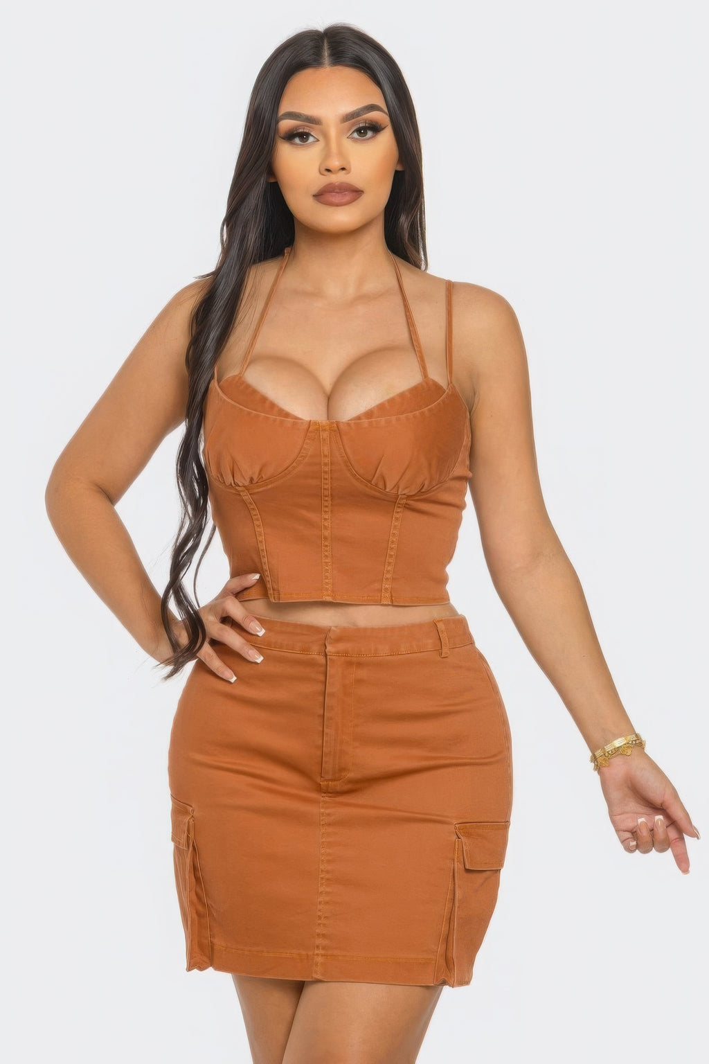 A model showcases a stylish three piece skirt set featuring a crop top and a fitted skirt in a warm brown color.