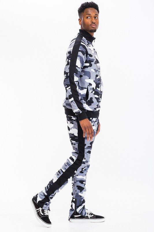 Man wearing a slim fit camo tracksuit set featuring a zip jacket and jogger pants, showcasing modern streetwear style.