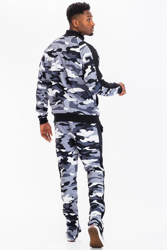 Model wearing a stylish camo tracksuit set featuring a zip jacket and jogger pants in black and grey camouflage.