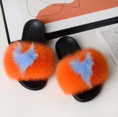 Plush faux fur slides in vibrant orange and blue, featuring a heart design, perfect for comfort and style.