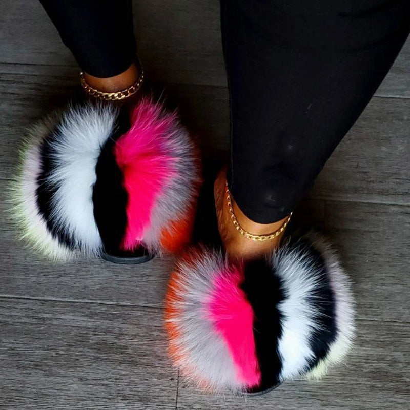 Colorful faux fur slides with bold pink, black, and white accents, perfect for stylish, cozy lounging.