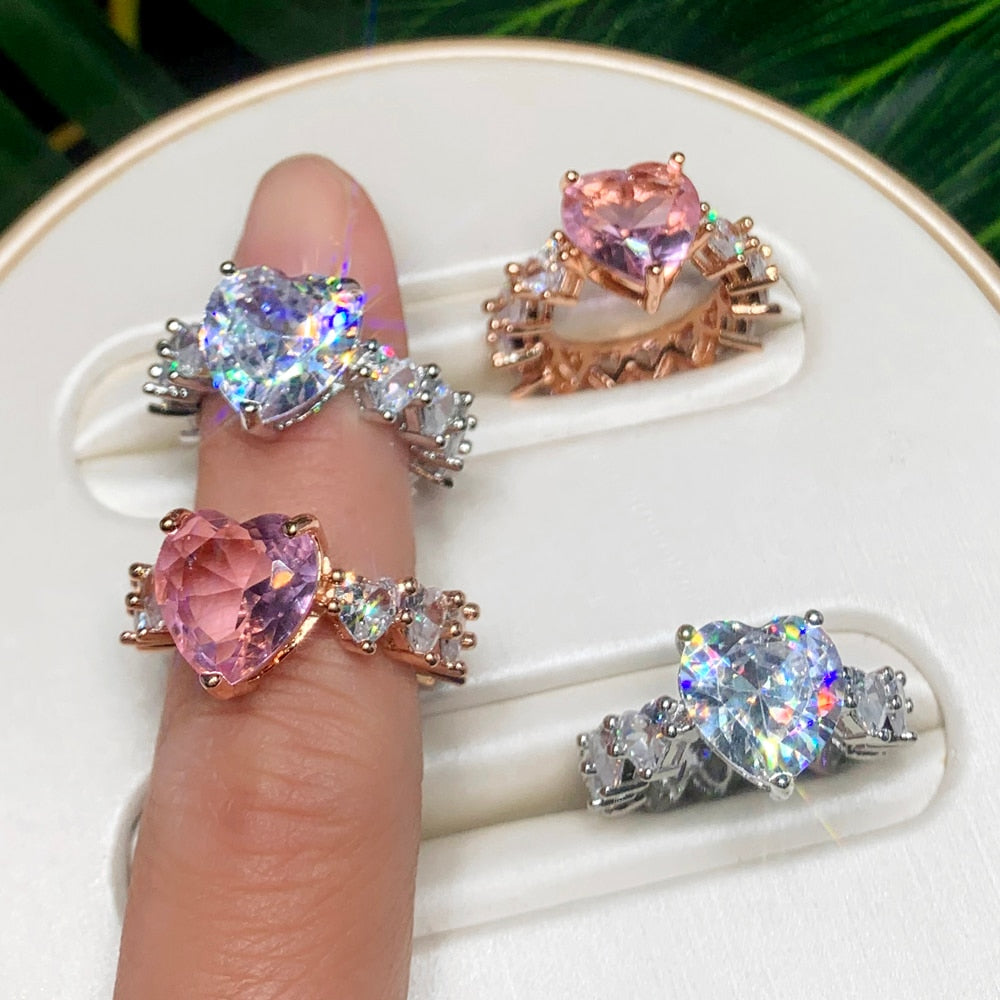 Beautiful display of cubic zirconia heart rings in various colors and styles on a finger.