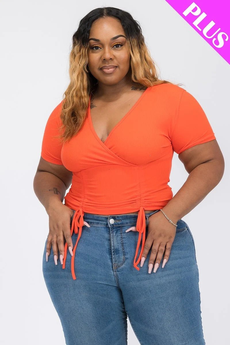 Model wearing a flattering wrap tie v-neck fitted shirt in orange with adjustable front ties and casual jeans.